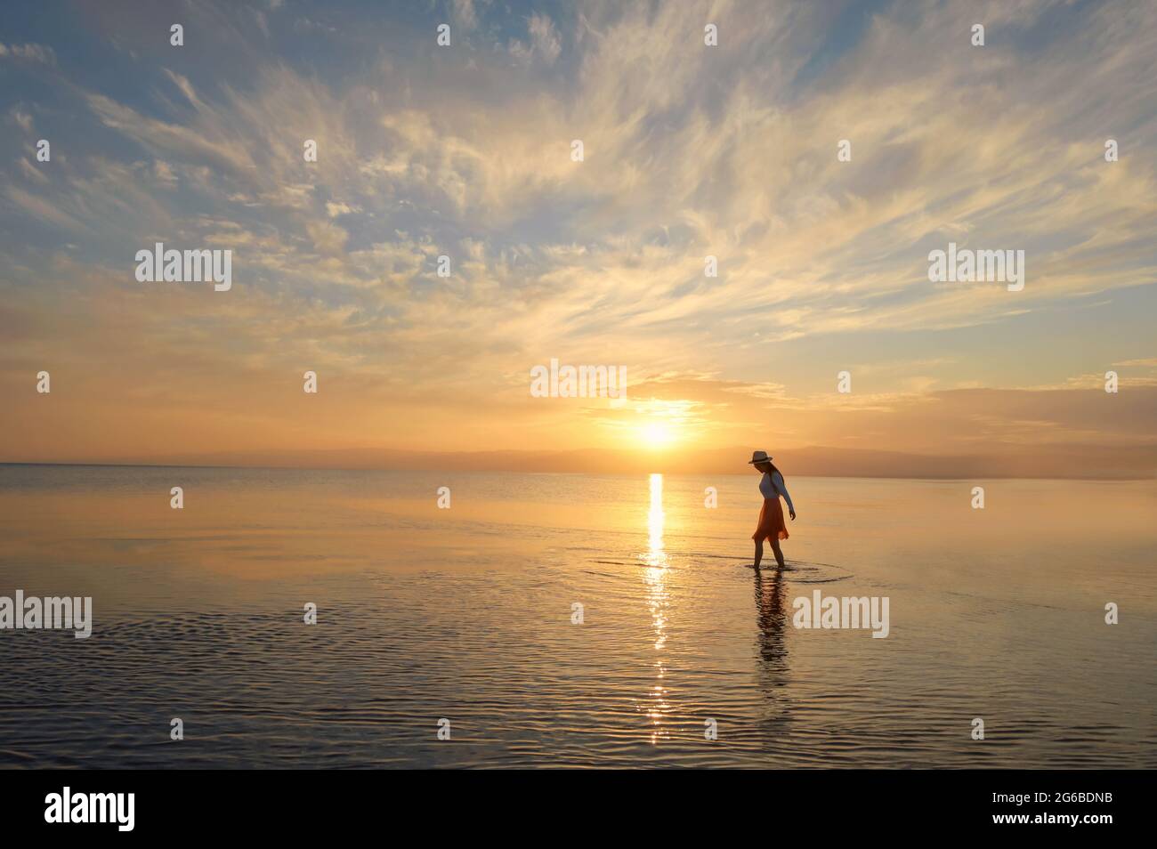 Frau, die bei Sonnenuntergang im Meer spazieren geht, Thailand Stockfoto