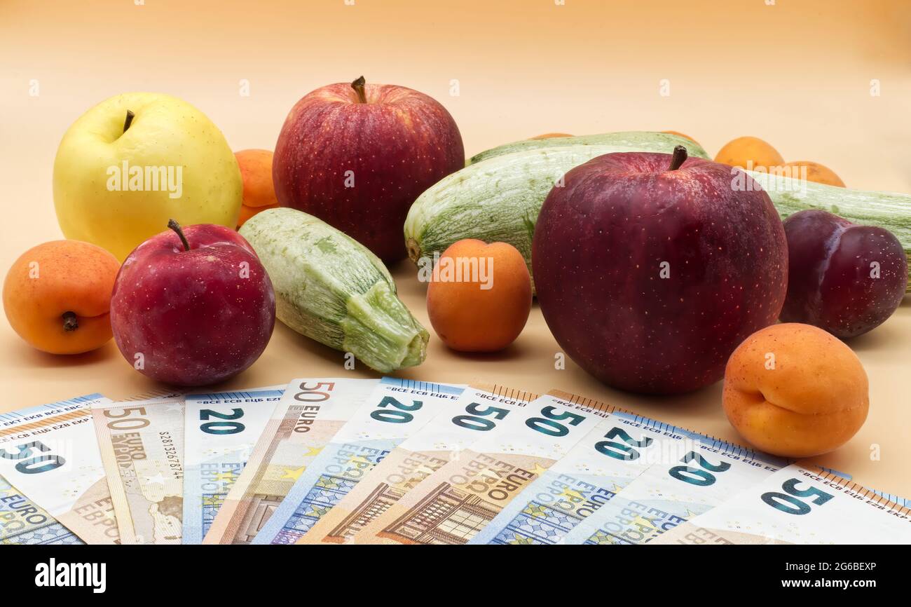 Obst und Gemüse sowie ein Haufen Euro-Banknoten. Und ein Haufen Euro-Banknoten. Kostenkonzept für Obst und Gemüse Stockfoto