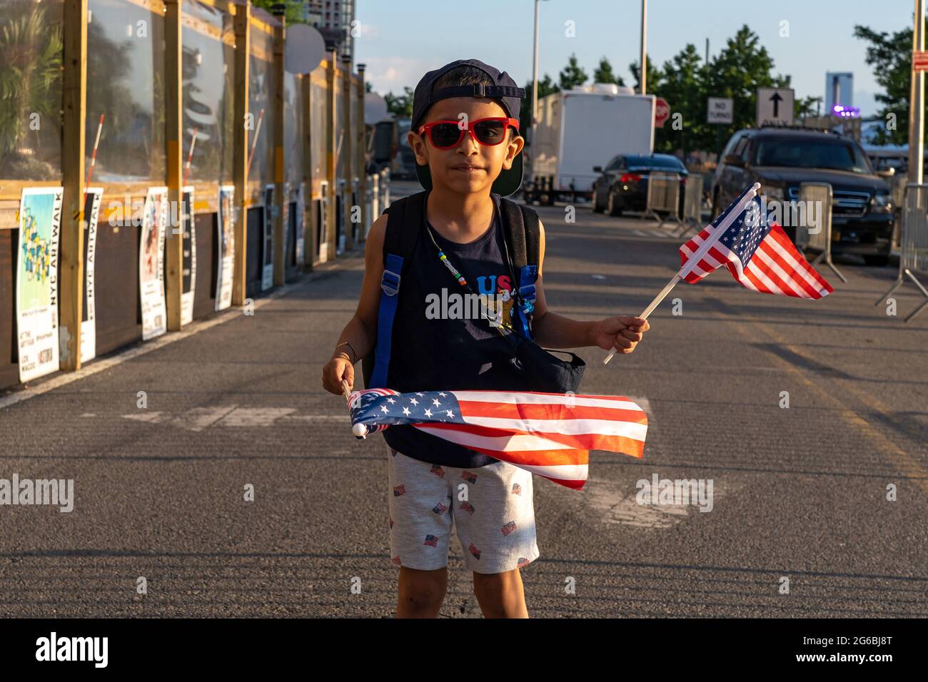 NEW YORK, NY - 04. JULI: Daniel, 6 Jahre alt, schwenkt amerikanische Flaggen während der 45. Jährlichen Macy's Feuerwerksausstellung am 4. Juli mit Blick auf die Skyline von Manhattan am Gantry State Plaza in Long Island City am 4. Juli 2021 im Stadtteil Queens von New York City. Als Beweis für die Verbesserung der Stadt gegenüber COVID-19 war die diesjährige Feier mit einer Laufzeit von 25 Minuten größer und länger als in den Vorjahren geplant. Aufgrund der Coronavirus-Pandemie des vergangenen Jahres wurde das Feuerwerk über vier Nächte und mehrere Bezirke verteilt, um Versammlungen zu begrenzen und die Ausbreitung zu verlangsamen. Kredit: Ron Adar/Alamy Stockfoto