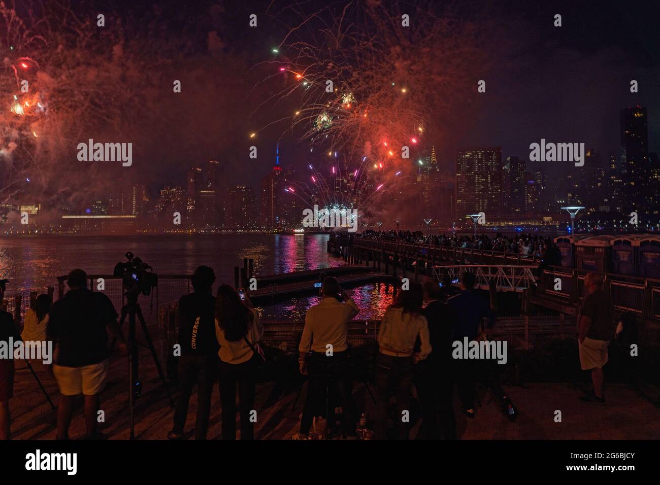 NEW YORK, NY - JULI 04: Zuschauer beobachten das Feuerwerk während der 45. Jährlichen Macy's Feuerwerksschau am 4. Juli 2021 mit Blick auf die Skyline von Manhattan am Gantry State Plaza in Long Island City im Stadtteil Queens von New York City. Als Beweis für die Verbesserung der Stadt gegenüber COVID-19 war die diesjährige Feier mit einer Laufzeit von 25 Minuten größer und länger als in den Vorjahren geplant. Aufgrund der Coronavirus-Pandemie des vergangenen Jahres wurde das Feuerwerk über vier Nächte und mehrere Bezirke verteilt, um Versammlungen zu begrenzen und die Ausbreitung zu verlangsamen. Kredit: Ron Adar/Alamy Stockfoto