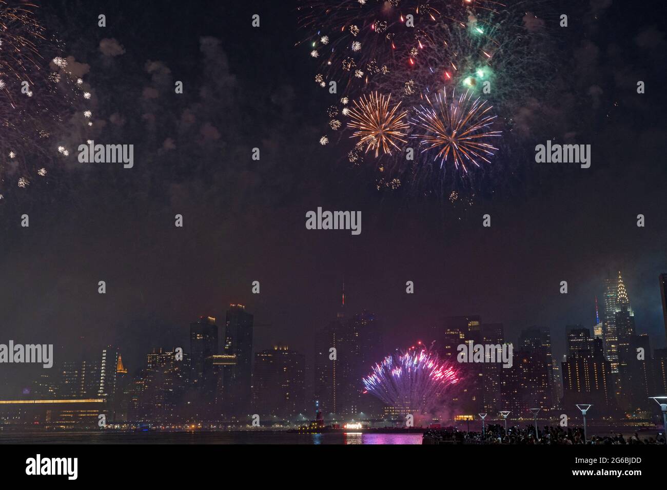 NEW YORK, NY - JULI 04: Zuschauer beobachten das Feuerwerk während der 45. Jährlichen Macy's Feuerwerksschau am 4. Juli 2021 mit Blick auf die Skyline von Manhattan am Gantry State Plaza in Long Island City im Stadtteil Queens von New York City. Als Beweis für die Verbesserung der Stadt gegenüber COVID-19 war die diesjährige Feier mit einer Laufzeit von 25 Minuten größer und länger als in den Vorjahren geplant. Aufgrund der Coronavirus-Pandemie des vergangenen Jahres wurde das Feuerwerk über vier Nächte und mehrere Bezirke verteilt, um Versammlungen zu begrenzen und die Ausbreitung zu verlangsamen. Kredit: Ron Adar/Alamy Stockfoto