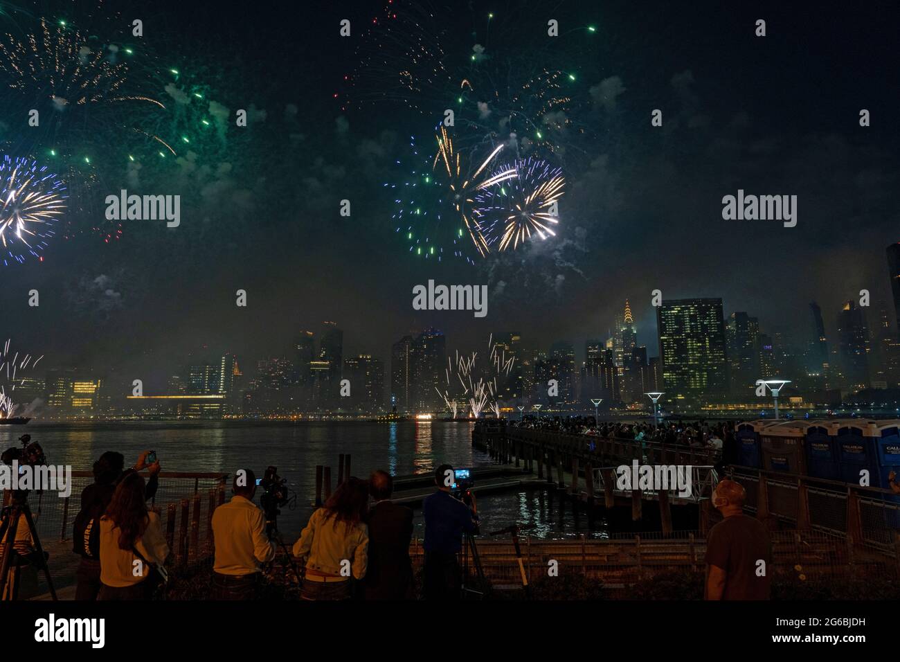 NEW YORK, NY - JULI 04: Zuschauer beobachten das Feuerwerk während der 45. Jährlichen Macy's Feuerwerksschau am 4. Juli 2021 mit Blick auf die Skyline von Manhattan am Gantry State Plaza in Long Island City im Stadtteil Queens von New York City. Als Beweis für die Verbesserung der Stadt gegenüber COVID-19 war die diesjährige Feier mit einer Laufzeit von 25 Minuten größer und länger als in den Vorjahren geplant. Aufgrund der Coronavirus-Pandemie des vergangenen Jahres wurde das Feuerwerk über vier Nächte und mehrere Bezirke verteilt, um Versammlungen zu begrenzen und die Ausbreitung zu verlangsamen. Kredit: Ron Adar/Alamy Stockfoto