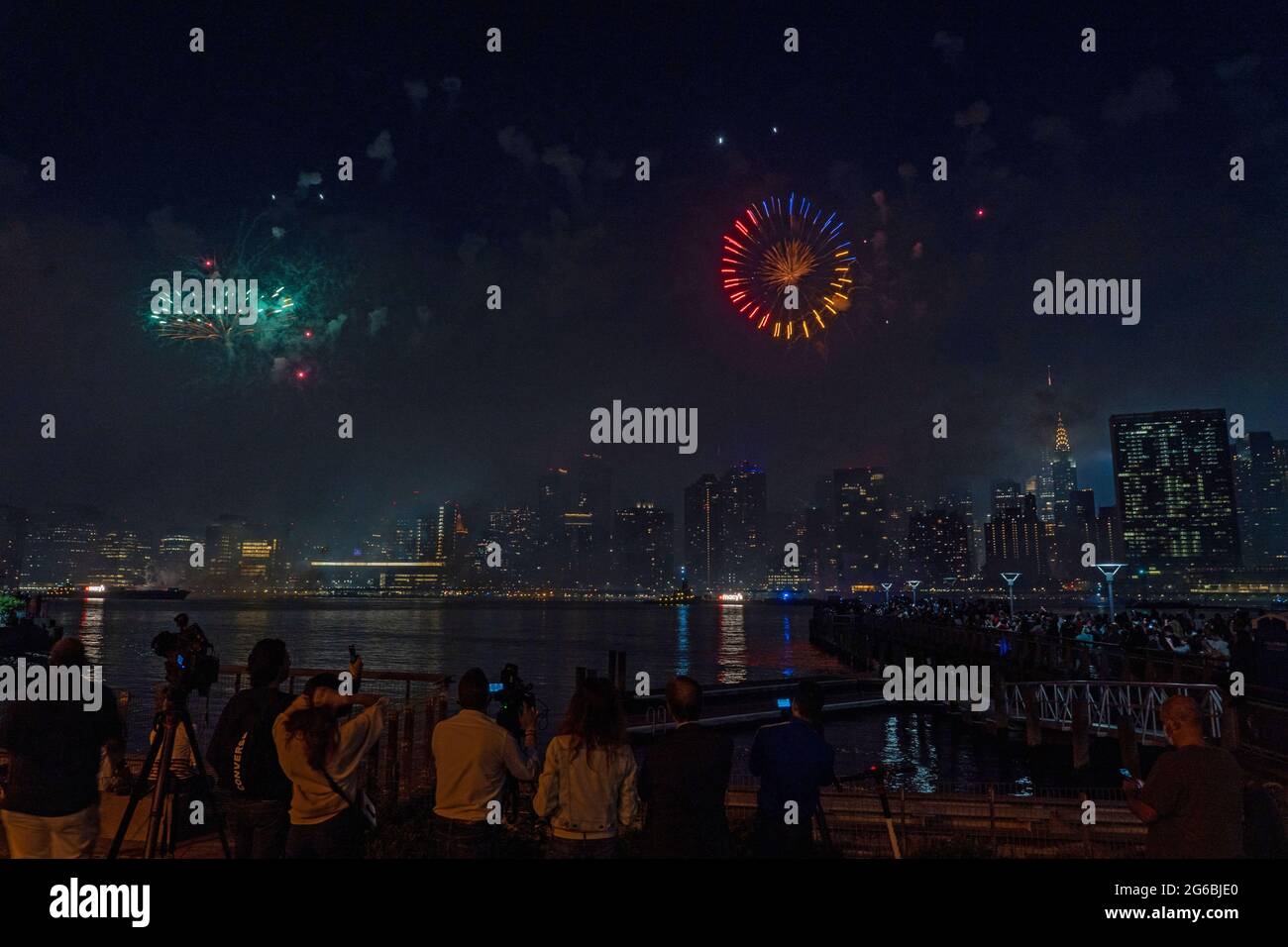 NEW YORK, NY - JULI 04: Zuschauer beobachten das Feuerwerk während der 45. Jährlichen Macy's Feuerwerksschau am 4. Juli 2021 mit Blick auf die Skyline von Manhattan am Gantry State Plaza in Long Island City im Stadtteil Queens von New York City. Als Beweis für die Verbesserung der Stadt gegenüber COVID-19 war die diesjährige Feier mit einer Laufzeit von 25 Minuten größer und länger als in den Vorjahren geplant. Aufgrund der Coronavirus-Pandemie des vergangenen Jahres wurde das Feuerwerk über vier Nächte und mehrere Bezirke verteilt, um Versammlungen zu begrenzen und die Ausbreitung zu verlangsamen. Kredit: Ron Adar/Alamy Stockfoto