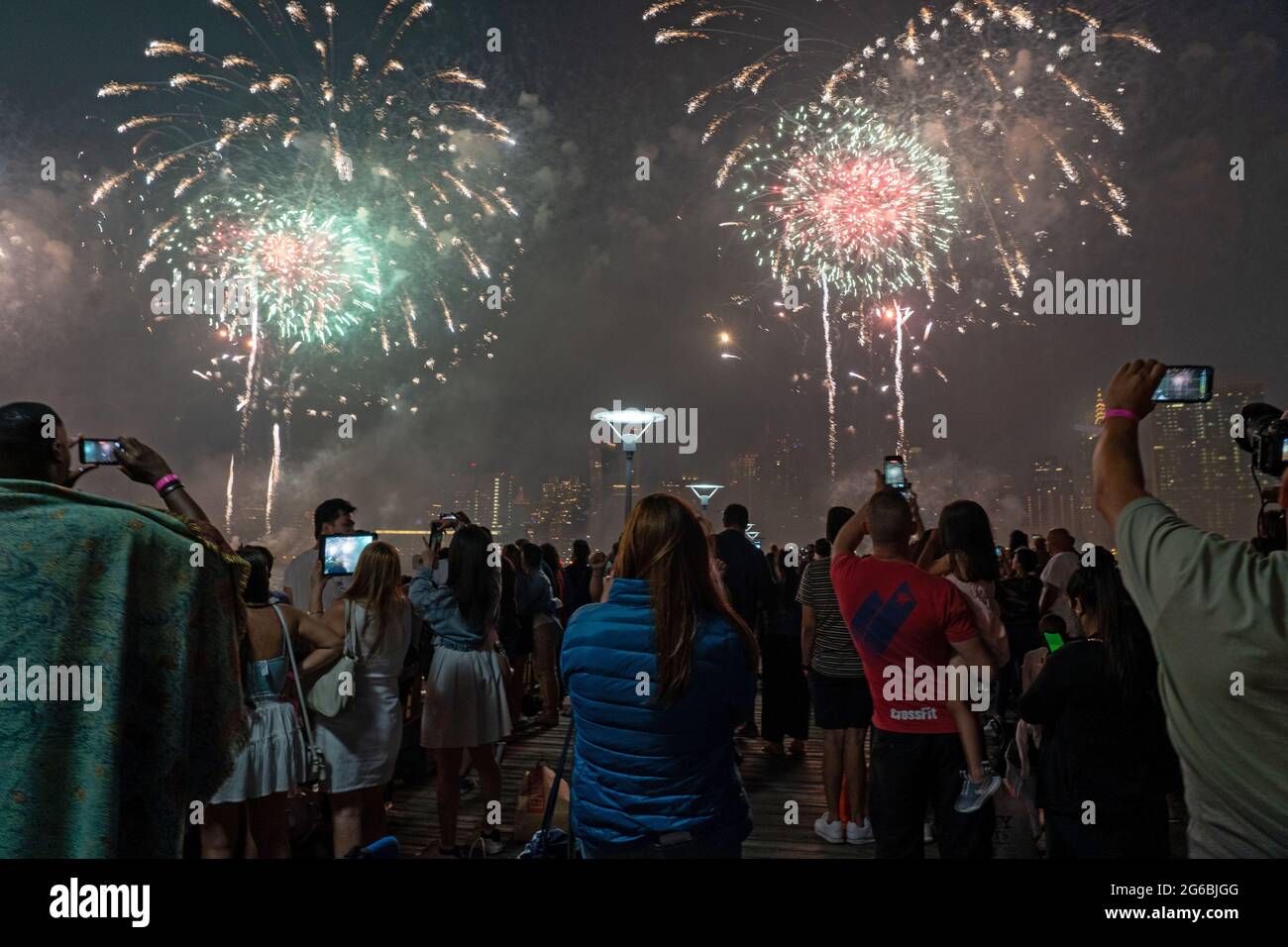 NEW YORK, NY - JULI 04: Zuschauer beobachten das Feuerwerk während der 45. Jährlichen Macy's Feuerwerksschau am 4. Juli 2021 mit Blick auf die Skyline von Manhattan am Gantry State Plaza in Long Island City im Stadtteil Queens von New York City. Als Beweis für die Verbesserung der Stadt gegenüber COVID-19 war die diesjährige Feier mit einer Laufzeit von 25 Minuten größer und länger als in den Vorjahren geplant. Aufgrund der Coronavirus-Pandemie des vergangenen Jahres wurde das Feuerwerk über vier Nächte und mehrere Bezirke verteilt, um Versammlungen zu begrenzen und die Ausbreitung zu verlangsamen. Kredit: Ron Adar/Alamy Stockfoto