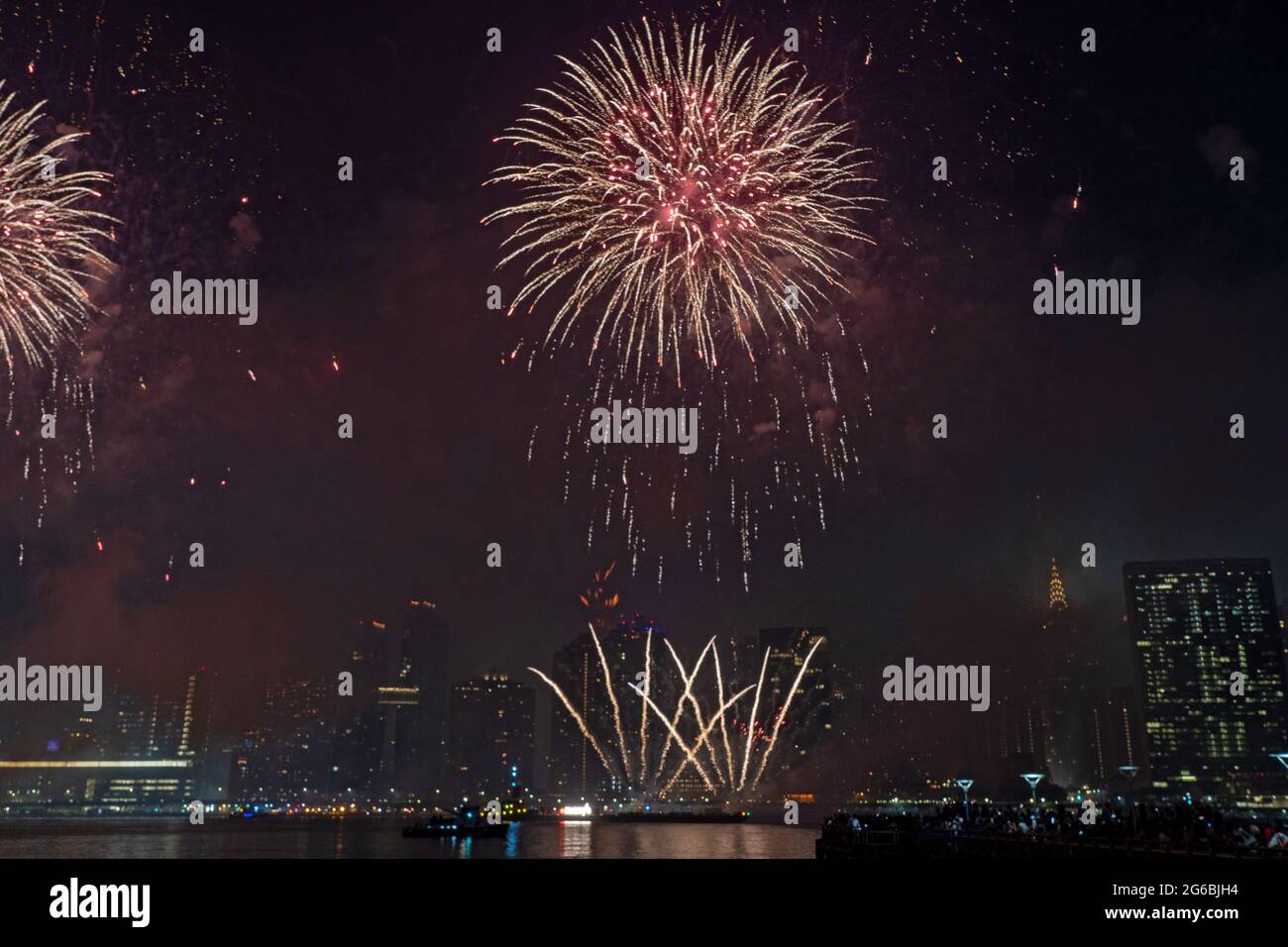 NEW YORK, NY - JULI 04: Zuschauer beobachten das Feuerwerk während der 45. Jährlichen Macy's Feuerwerksschau am 4. Juli 2021 mit Blick auf die Skyline von Manhattan am Gantry State Plaza in Long Island City im Stadtteil Queens von New York City. Als Beweis für die Verbesserung der Stadt gegenüber COVID-19 war die diesjährige Feier mit einer Laufzeit von 25 Minuten größer und länger als in den Vorjahren geplant. Aufgrund der Coronavirus-Pandemie des vergangenen Jahres wurde das Feuerwerk über vier Nächte und mehrere Bezirke verteilt, um Versammlungen zu begrenzen und die Ausbreitung zu verlangsamen. Kredit: Ron Adar/Alamy Stockfoto