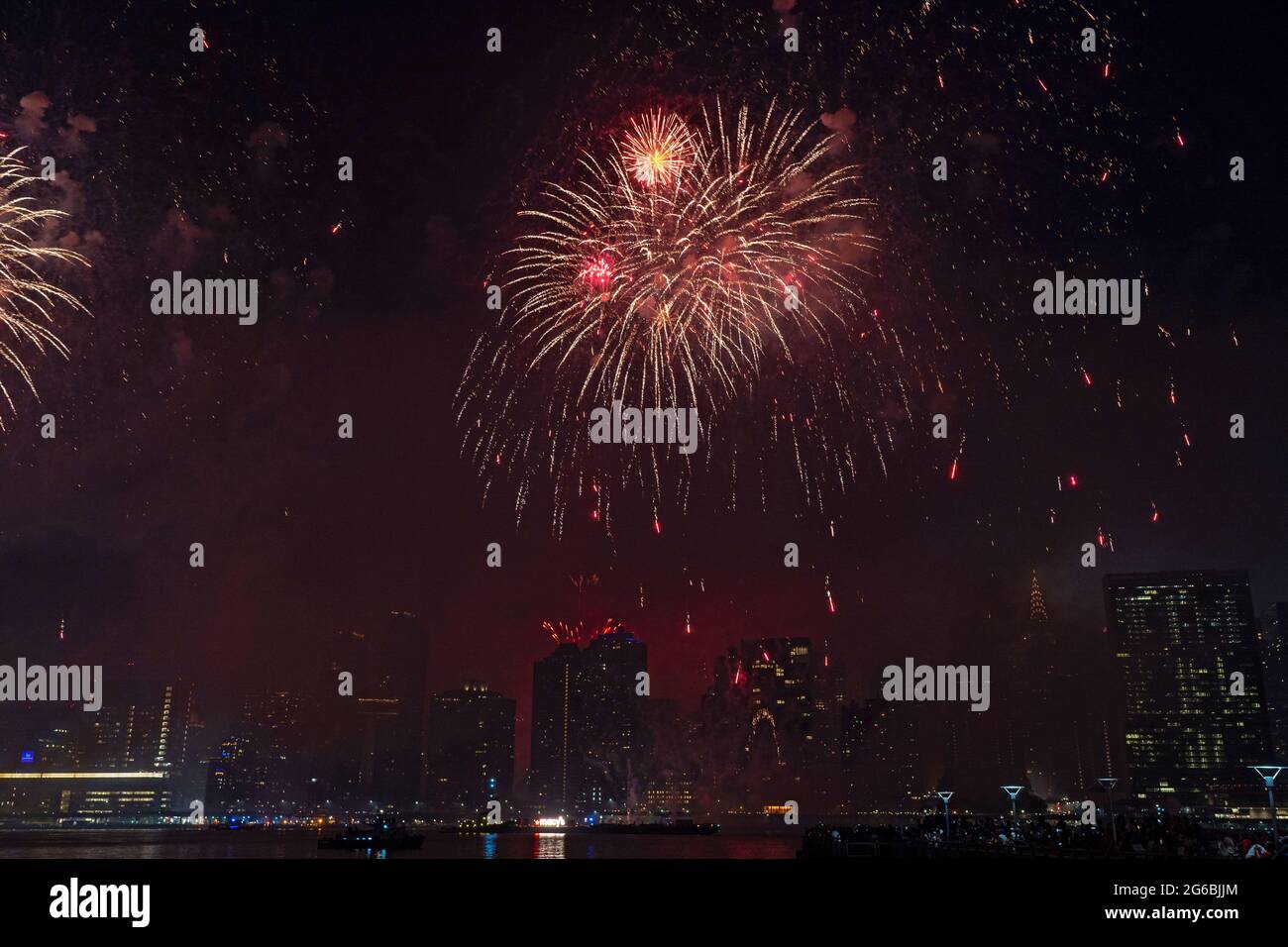 NEW YORK, NY - JULI 04: Zuschauer beobachten das Feuerwerk während der 45. Jährlichen Macy's Feuerwerksschau am 4. Juli 2021 mit Blick auf die Skyline von Manhattan am Gantry State Plaza in Long Island City im Stadtteil Queens von New York City. Als Beweis für die Verbesserung der Stadt gegenüber COVID-19 war die diesjährige Feier mit einer Laufzeit von 25 Minuten größer und länger als in den Vorjahren geplant. Aufgrund der Coronavirus-Pandemie des vergangenen Jahres wurde das Feuerwerk über vier Nächte und mehrere Bezirke verteilt, um Versammlungen zu begrenzen und die Ausbreitung zu verlangsamen. Kredit: Ron Adar/Alamy Stockfoto