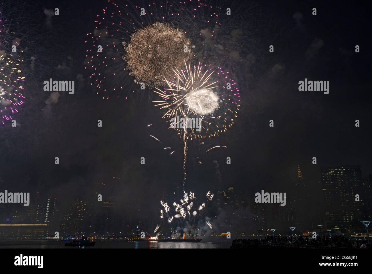 NEW YORK, NY - JULI 04: Zuschauer beobachten das Feuerwerk während der 45. Jährlichen Macy's Feuerwerksschau am 4. Juli 2021 mit Blick auf die Skyline von Manhattan am Gantry State Plaza in Long Island City im Stadtteil Queens von New York City. Als Beweis für die Verbesserung der Stadt gegenüber COVID-19 war die diesjährige Feier mit einer Laufzeit von 25 Minuten größer und länger als in den Vorjahren geplant. Aufgrund der Coronavirus-Pandemie des vergangenen Jahres wurde das Feuerwerk über vier Nächte und mehrere Bezirke verteilt, um Versammlungen zu begrenzen und die Ausbreitung zu verlangsamen. Kredit: Ron Adar/Alamy Stockfoto