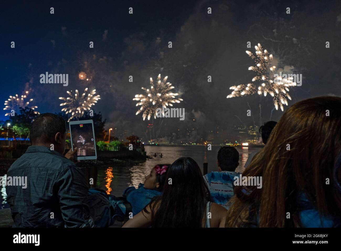 NEW YORK, NY - JULI 04: Zuschauer beobachten das Feuerwerk während der 45. Jährlichen Macy's Feuerwerksschau am 4. Juli 2021 mit Blick auf die Skyline von Manhattan am Gantry State Plaza in Long Island City im Stadtteil Queens von New York City. Als Beweis für die Verbesserung der Stadt gegenüber COVID-19 war die diesjährige Feier mit einer Laufzeit von 25 Minuten größer und länger als in den Vorjahren geplant. Aufgrund der Coronavirus-Pandemie des vergangenen Jahres wurde das Feuerwerk über vier Nächte und mehrere Bezirke verteilt, um Versammlungen zu begrenzen und die Ausbreitung zu verlangsamen. Kredit: Ron Adar/Alamy Stockfoto