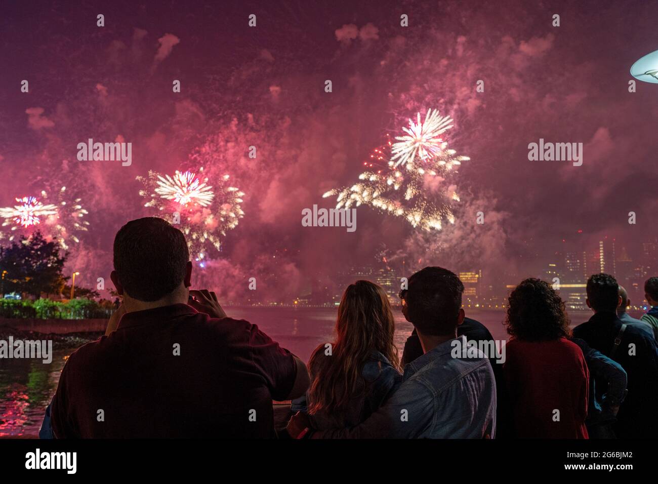 NEW YORK, NY - JULI 04: Zuschauer beobachten das Feuerwerk während der 45. Jährlichen Macy's Feuerwerksschau am 4. Juli 2021 mit Blick auf die Skyline von Manhattan am Gantry State Plaza in Long Island City im Stadtteil Queens von New York City. Als Beweis für die Verbesserung der Stadt gegenüber COVID-19 war die diesjährige Feier mit einer Laufzeit von 25 Minuten größer und länger als in den Vorjahren geplant. Aufgrund der Coronavirus-Pandemie des vergangenen Jahres wurde das Feuerwerk über vier Nächte und mehrere Bezirke verteilt, um Versammlungen zu begrenzen und die Ausbreitung zu verlangsamen. Kredit: Ron Adar/Alamy Stockfoto