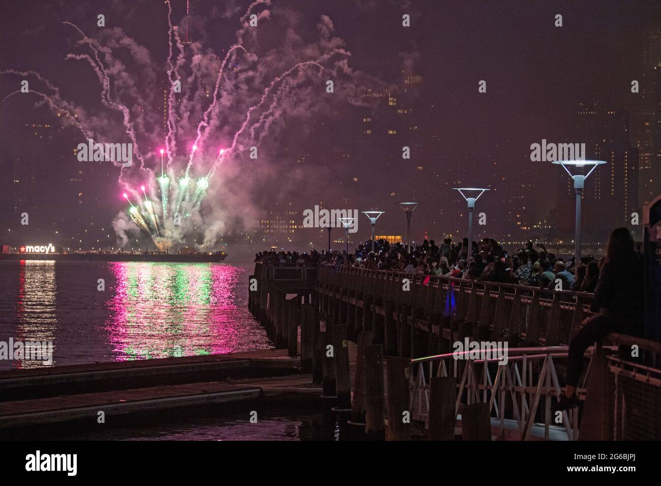 NEW YORK, NY - JULI 04: Zuschauer beobachten das Feuerwerk während der 45. Jährlichen Macy's Feuerwerksschau am 4. Juli 2021 mit Blick auf die Skyline von Manhattan am Gantry State Plaza in Long Island City im Stadtteil Queens von New York City. Als Beweis für die Verbesserung der Stadt gegenüber COVID-19 war die diesjährige Feier mit einer Laufzeit von 25 Minuten größer und länger als in den Vorjahren geplant. Aufgrund der Coronavirus-Pandemie des vergangenen Jahres wurde das Feuerwerk über vier Nächte und mehrere Bezirke verteilt, um Versammlungen zu begrenzen und die Ausbreitung zu verlangsamen. Kredit: Ron Adar/Alamy Stockfoto