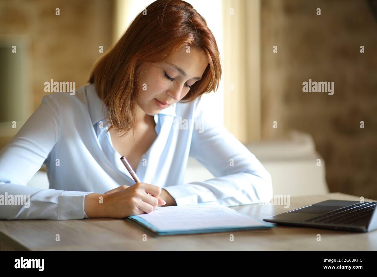 Konzentrierter Unternehmer, der den Vertrag unterzeichnet, sitzt zu Hause Stockfoto
