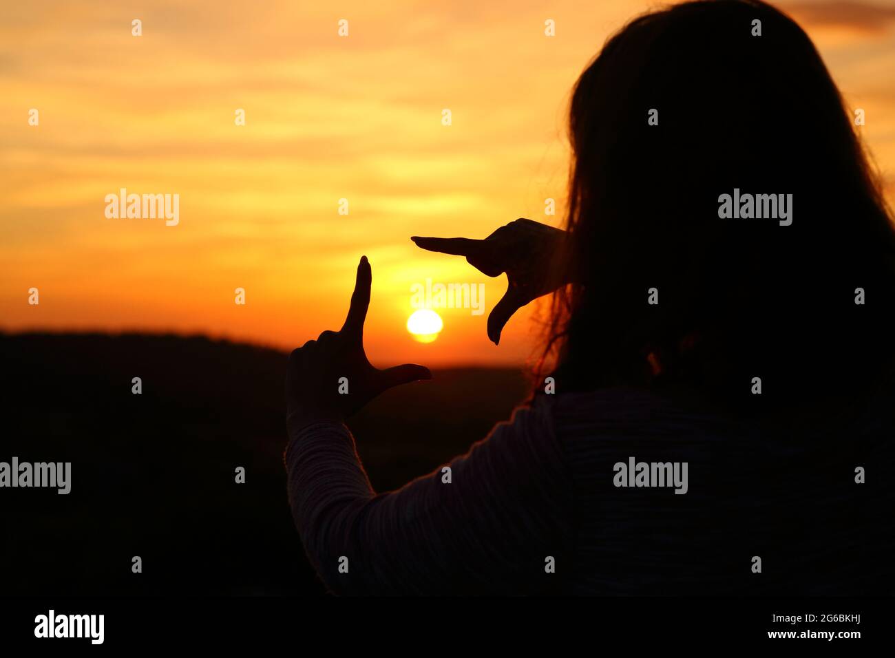 Hintergrundbeleuchtetes Porträt einer Frau Hände Silhouette Rahmen Sonne bei Sonnenuntergang Stockfoto