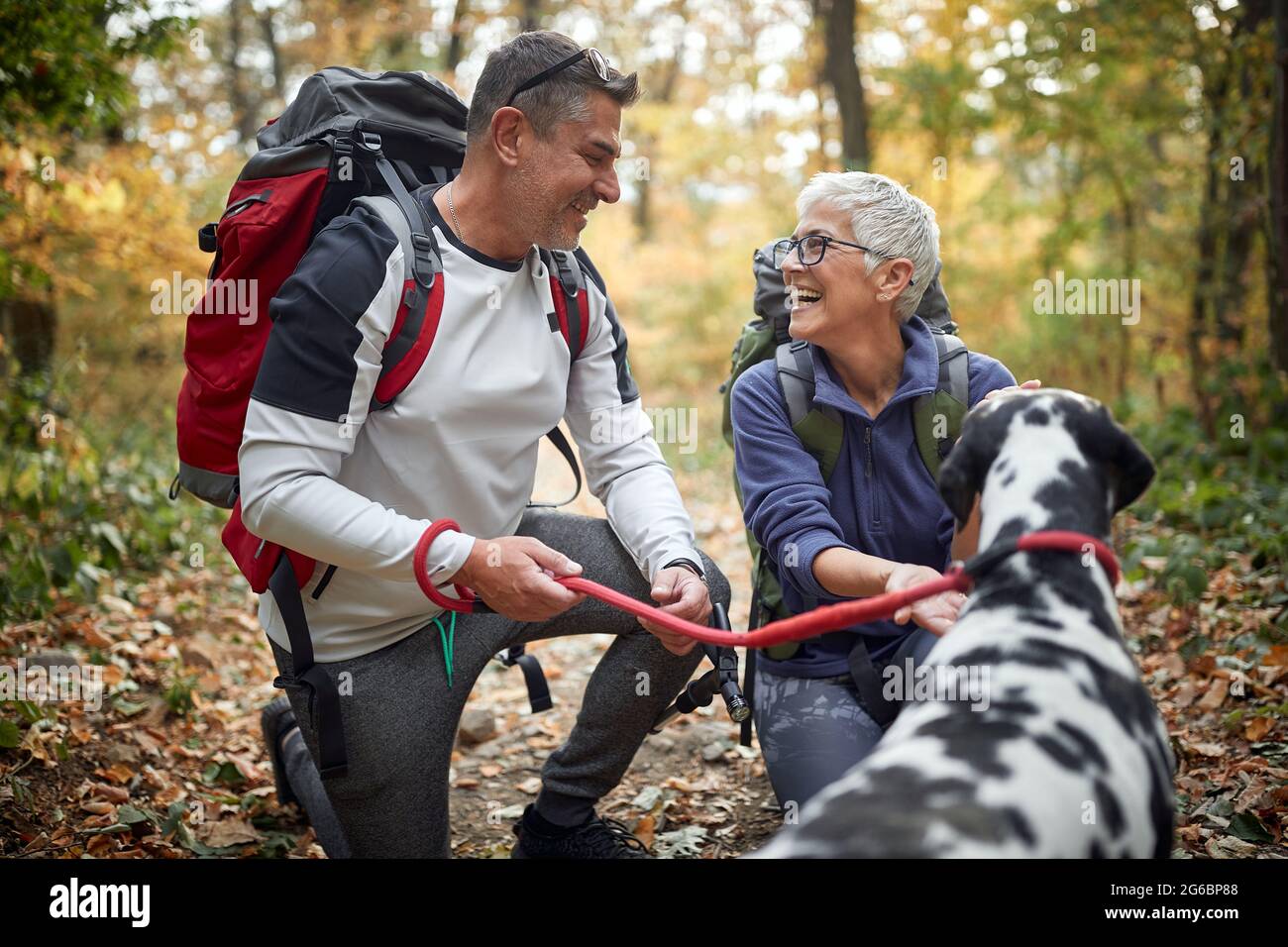 Ein älteres Wanderpaar und ihr Hund genießen eine Wanderung an einem schönen Herbsttag Stockfoto
