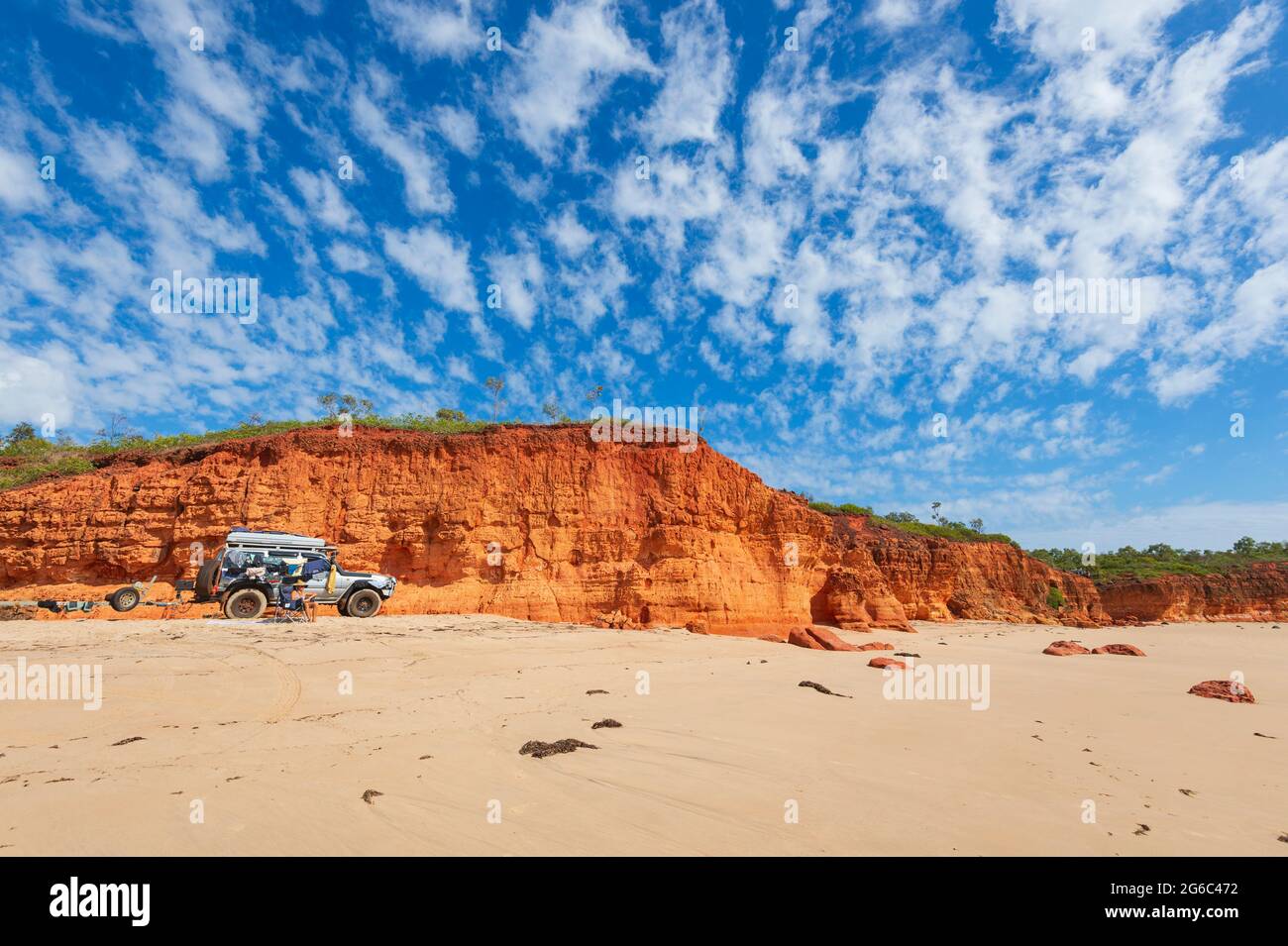 Allradantrieb am Strand mit einer Frau, die auf einem Stuhl saß, Pender Bay Escape, Dampier Peninsula, Western Australia, WA, Australien Stockfoto