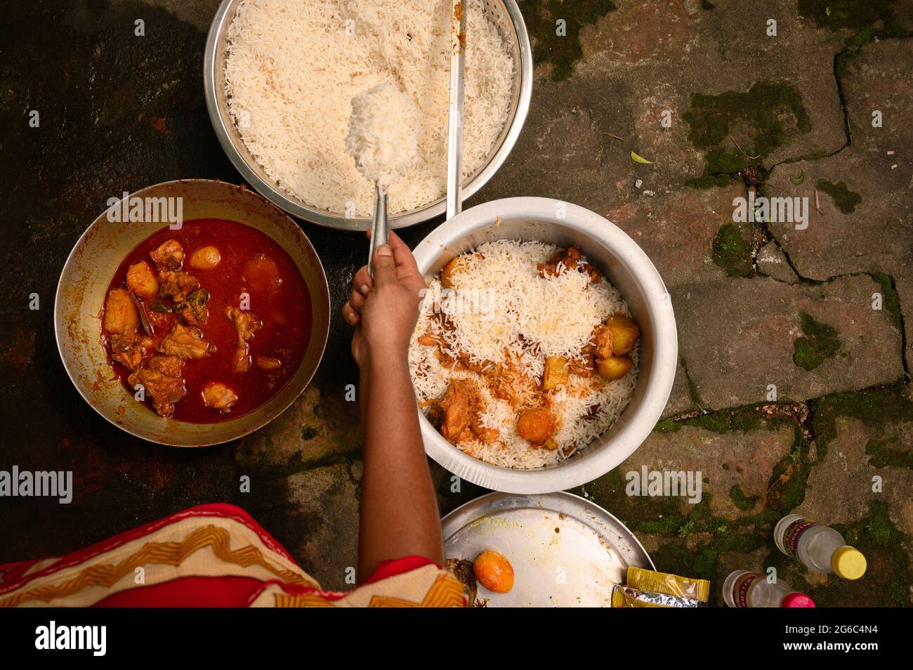 Eine Frau kocht Biryani. Biryani ist ein indo-arisches Wort, das vom persischen Wort „Birian“ abgeleitet wurde, was ‘vor dem Kochen gebraten’ und „Birinj“, das persische Wort für Reis, bedeutet. Die Biryani ist eines der beliebtesten und bestellten Gerichte in Indien. Es wird mit indischen Gewürzen, Reis und Fleisch (Huhn, Rindfleisch, Ziege, Lamm, Garnelen, Fisch), und manchmal, zusätzlich, Eier oder Gemüse wie Kartoffeln in bestimmten regionalen Sorten. Es gibt verschiedene Theorien über die Herkunft dieses leckeren Gerichts. Viele Historiker glauben, dass Biryani aus Persien stammte und von den Moguln nach Indien gebracht wurde. Stockfoto