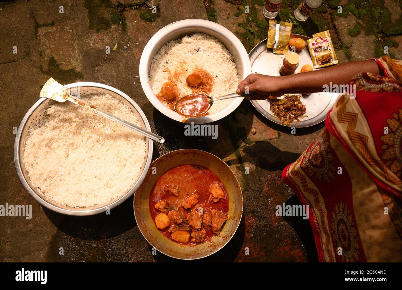 Eine Frau kocht Biryani. Biryani ist ein indo-arisches Wort, das vom persischen Wort „Birian“ abgeleitet wurde, was ‘vor dem Kochen gebraten’ und „Birinj“, das persische Wort für Reis, bedeutet. Die Biryani ist eines der beliebtesten und bestellten Gerichte in Indien. Es wird mit indischen Gewürzen, Reis und Fleisch (Huhn, Rindfleisch, Ziege, Lamm, Garnelen, Fisch), und manchmal, zusätzlich, Eier oder Gemüse wie Kartoffeln in bestimmten regionalen Sorten. Es gibt verschiedene Theorien über die Herkunft dieses leckeren Gerichts. Viele Historiker glauben, dass Biryani aus Persien stammte und von den Moguln nach Indien gebracht wurde. Stockfoto