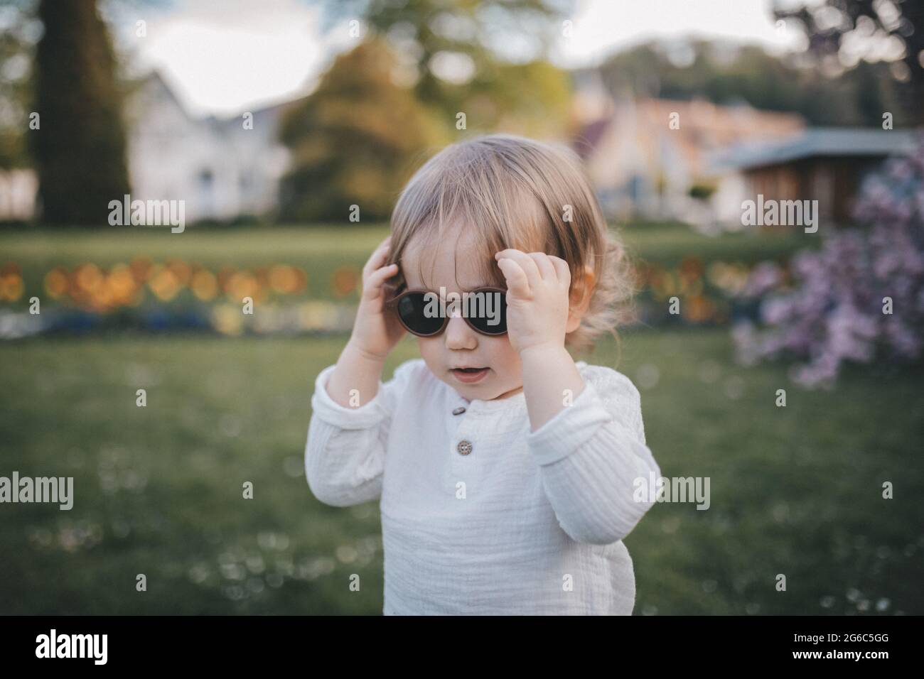 Kleiner Junge mit Sonnenbrille läuft im Garten. Stockfoto