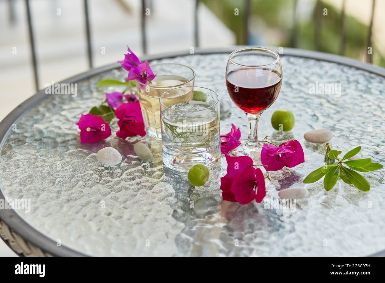 Im Sommer helle Cocktails und ein Glas Rotwein und rosa Blumen von Bougainvillea Dekorationen mit Kieselsteinen. Sommer Tapete aus nächster Nähe. Stockfoto