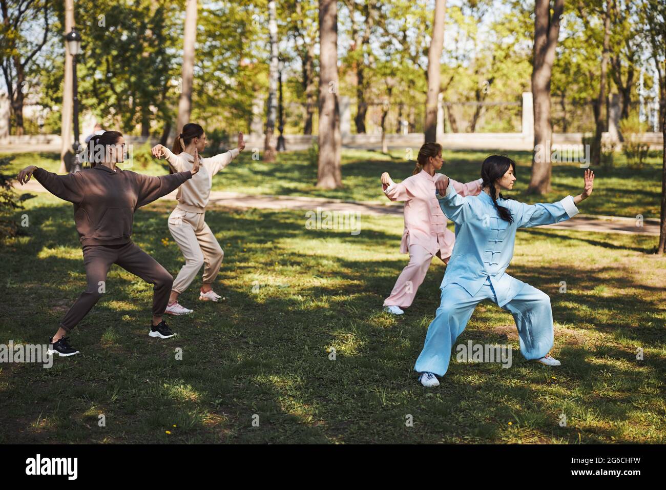 Vier Menschen machen Tai Chi-Übungen auf Gras im Freien Stockfoto