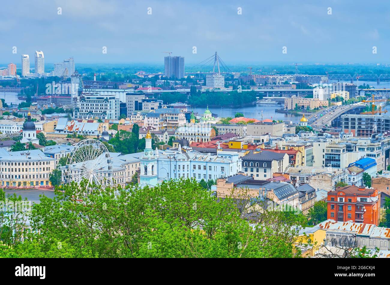 Die Dächer des historischen Podil-Viertels, das Riesenrad, der Dnjepr-Fluss und die Nordbrücke am Horizont, Kiew, Ukraine Stockfoto
