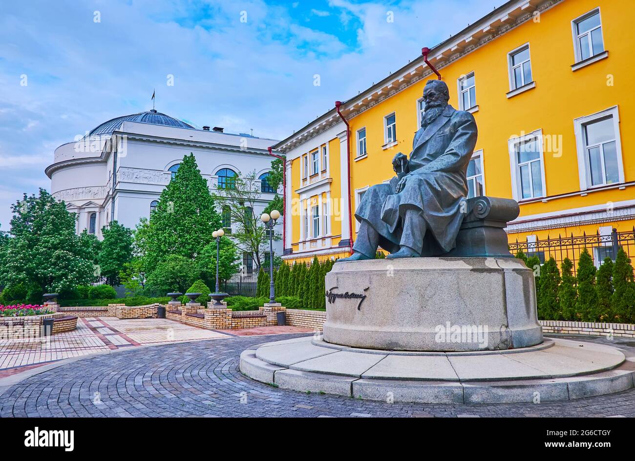 KIEW, UKRAINE - 18. MAI 2021: Das Denkmal für Mychailo Hrushevsky, angrenzend an das Gebäude der Taras Schewtschenko Universität und das Lehrerhaus (f Stockfoto