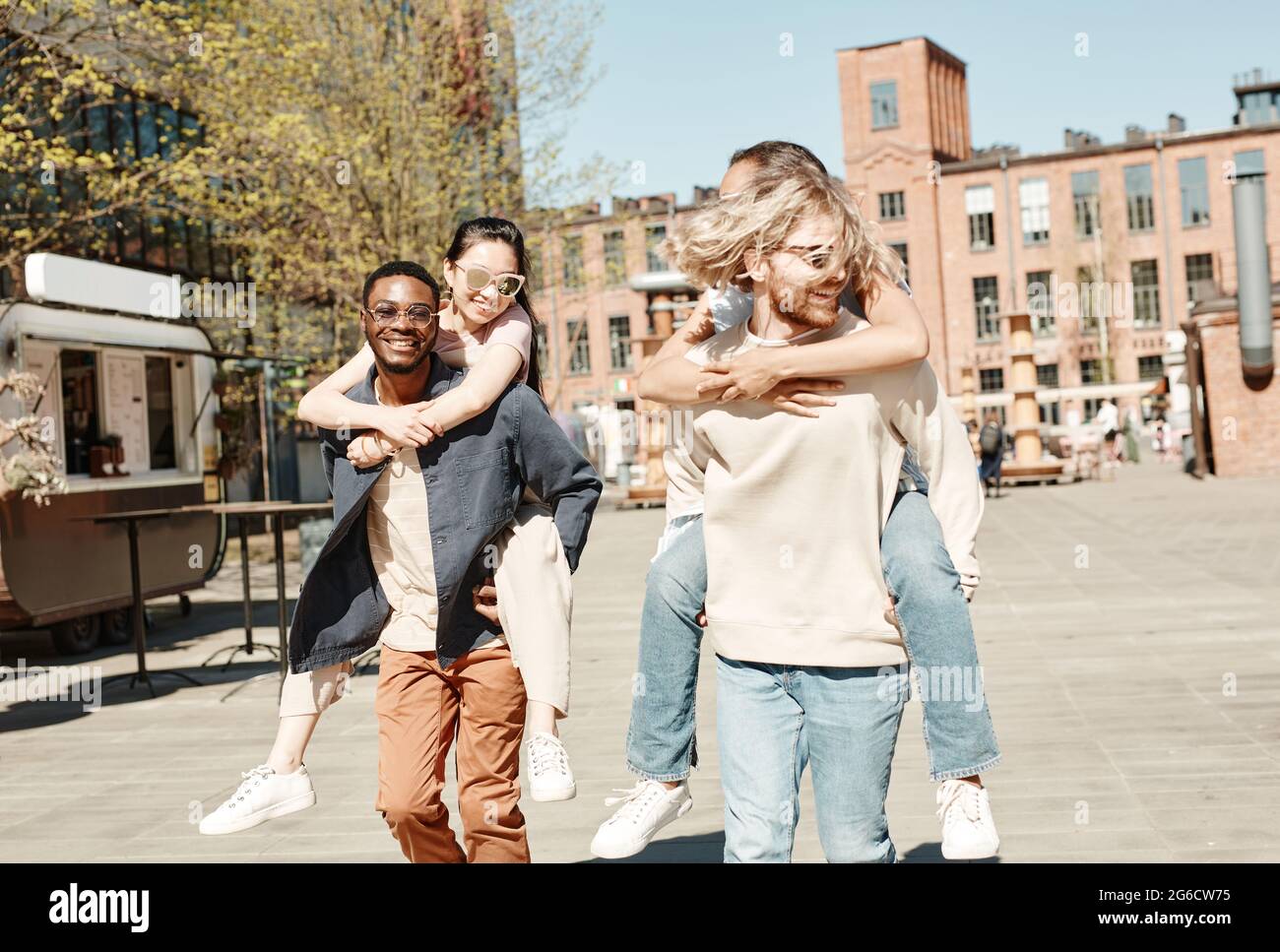 Waist-up-Porträt von zwei sorglosen jungen Paaren, die Spaß in der Sommerstadt haben Stockfoto