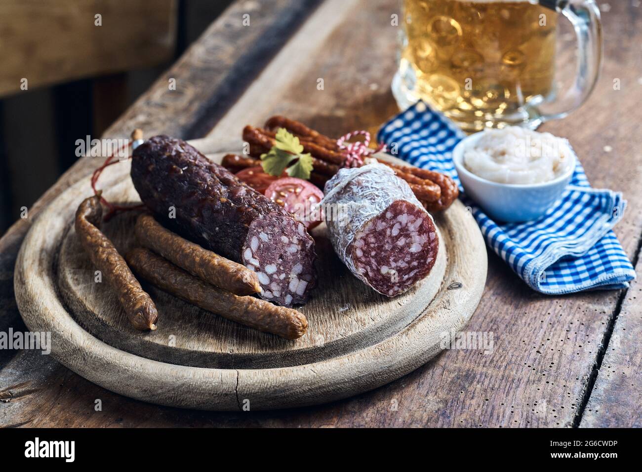 Ein großer Winkel appetitlich geräucherter Wildwurst, serviert auf Holzbrett mit einem Pint Bier Stockfoto