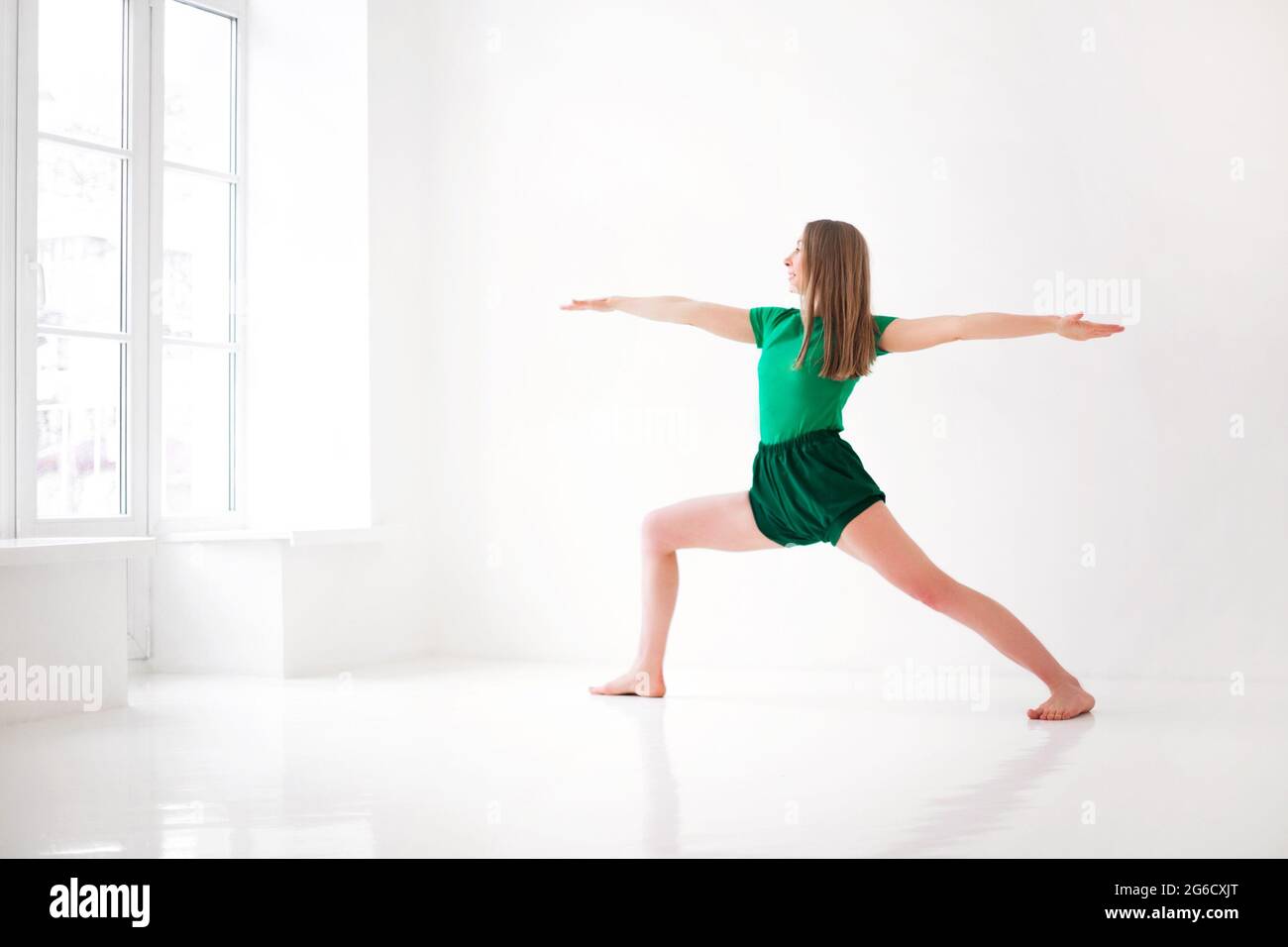 Ruhige Frau in Sportkleidung, die in Firefly Pose Yoga praktiziert, während sie ausbalanciert und wegschaut Stockfoto