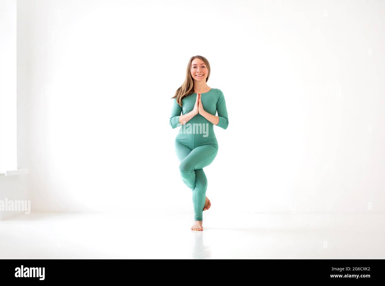 Ruhige Frau in Sportkleidung, die in Firefly Pose Yoga praktiziert, während sie ausbalanciert und wegschaut Stockfoto
