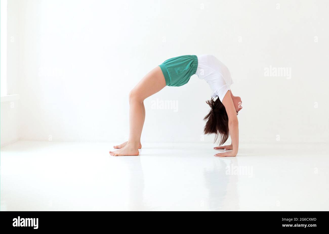 Seitenansicht einer ruhigen Frau in Sportkleidung, die Yoga in Pose praktiziert, während sie auf den Armen balanciert und wegschaut Stockfoto
