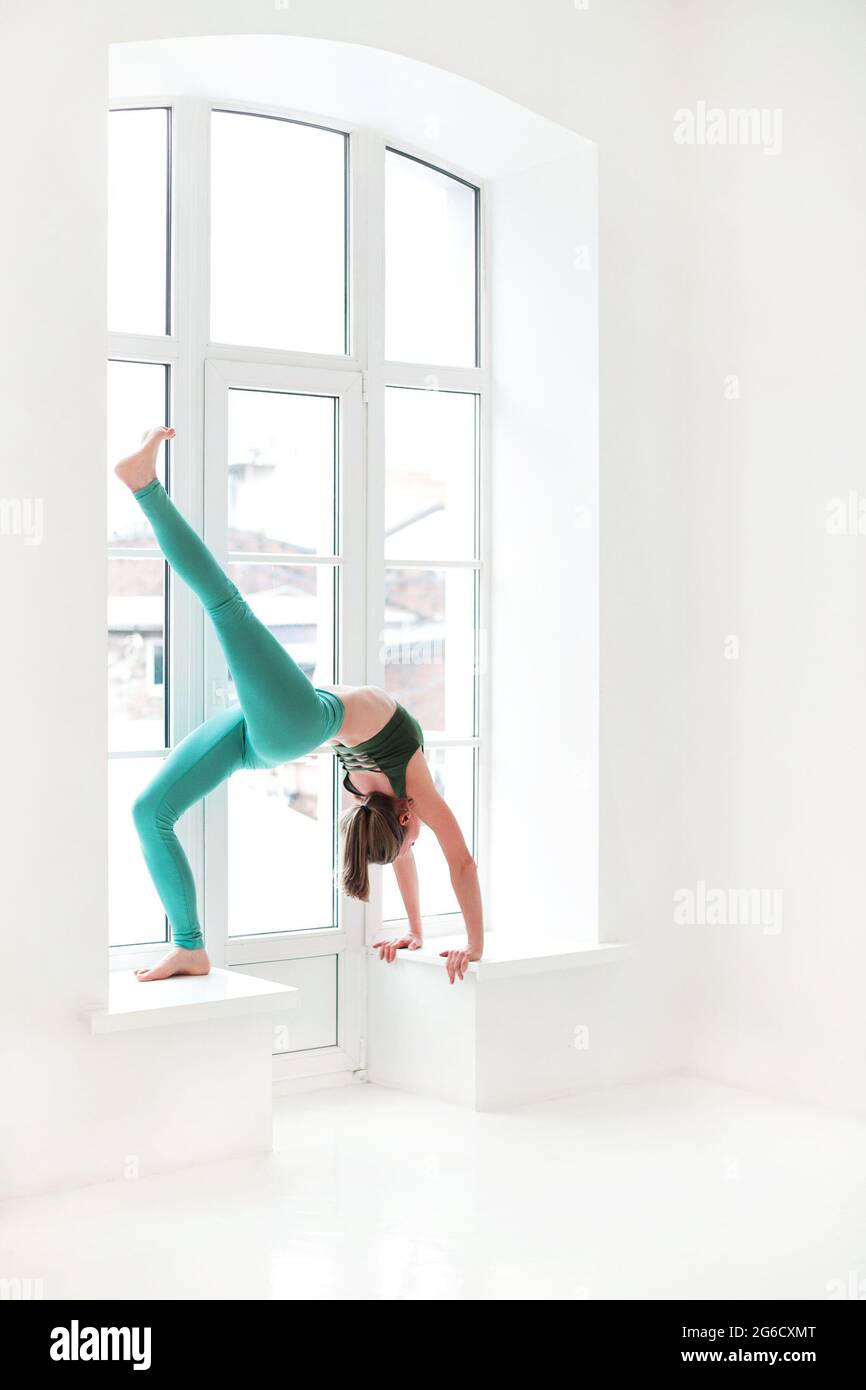 Seitenansicht einer ruhigen Frau in Sportkleidung, die Yoga in Pose praktiziert, während sie auf den Armen balanciert und wegschaut Stockfoto
