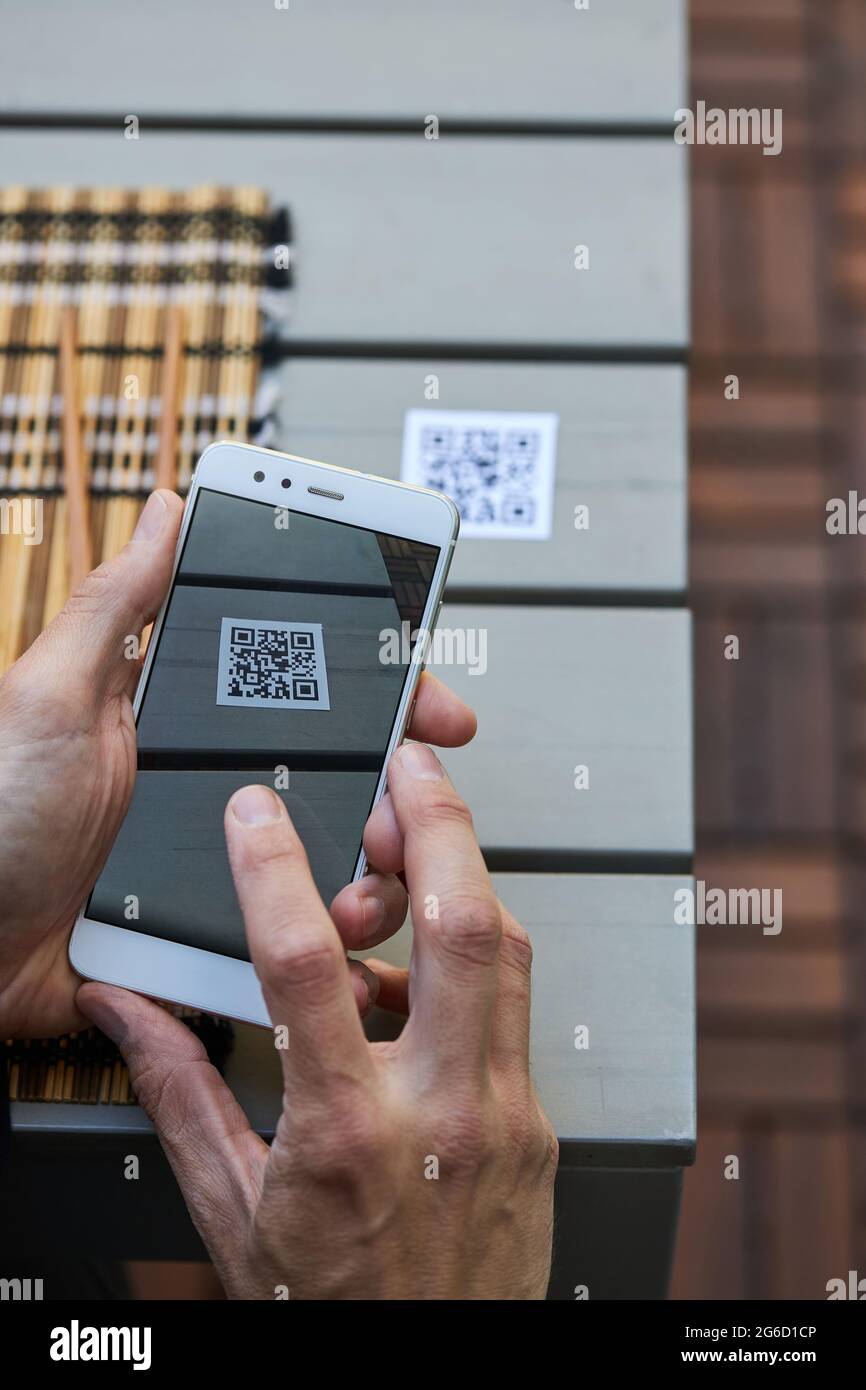 Von oben der Ernte unkenntlich männlich mit Smartphone und Scannen QR-Code des Menüs des Restaurants Stockfoto