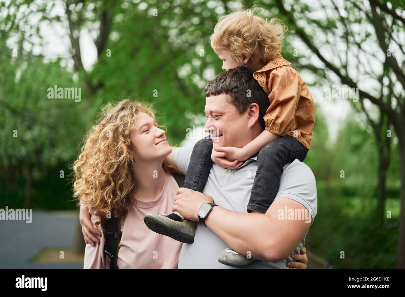 Entzückendes liebevolles Paar mit entzückenden Kindern, die Zeit zusammen im Sommerpark verbringen und das Wochenende genießen Stockfoto