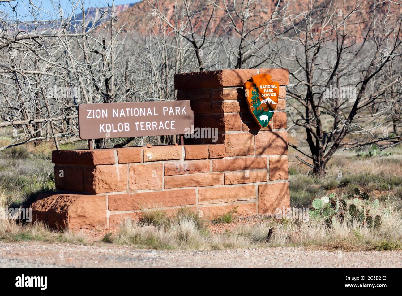 Zion National Park, Utah / USA - 4. November 2014: Ein rotes Felsschild für die Kolob Terrace Eingang zum Zion National Park mit herzerfalllicher Wüstenlandschaft i Stockfoto
