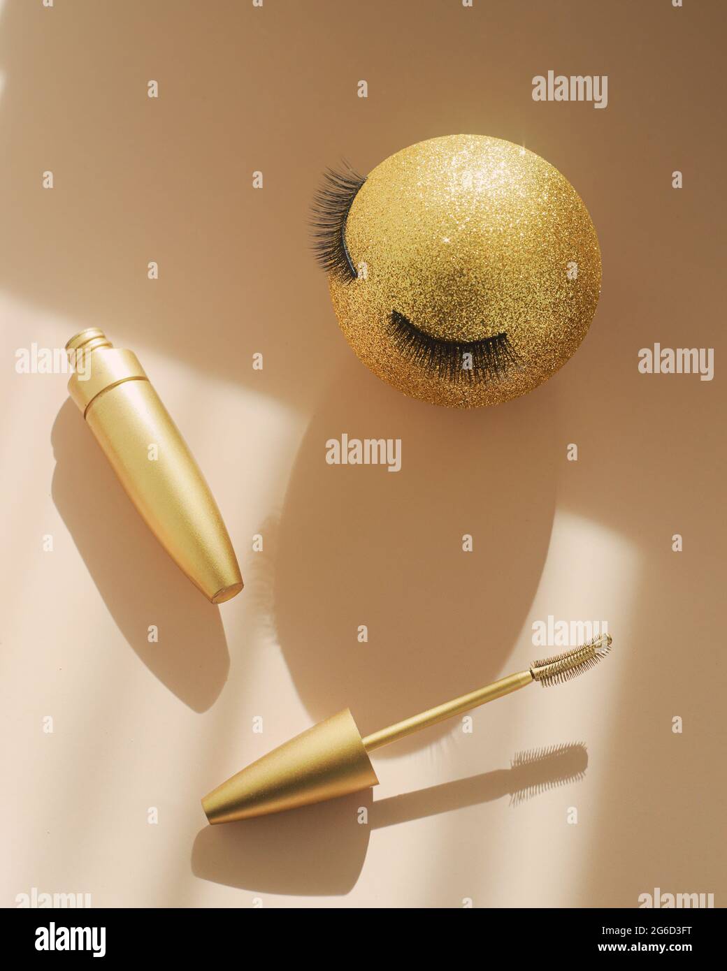 Mascara und ein goldener Weihnachtsball mit falschen Wimpern. Das Konzept der festlichen Make-up für Frauen. Make-up Artist Services Stockfoto