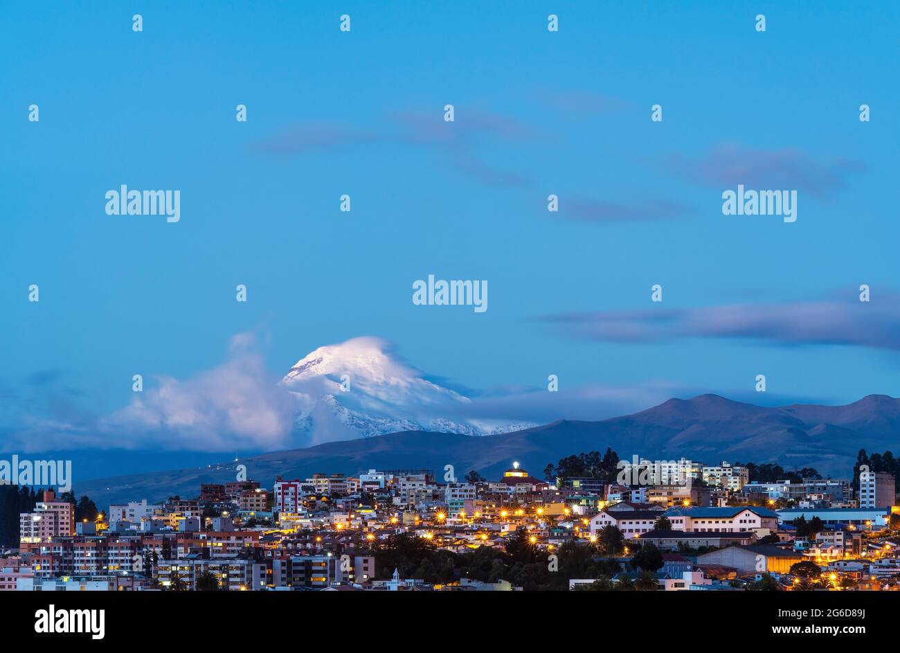 Quito Stadt in der Nacht während der blauen Stunde mit Vulkan Cayambe, Ecuador. Stockfoto