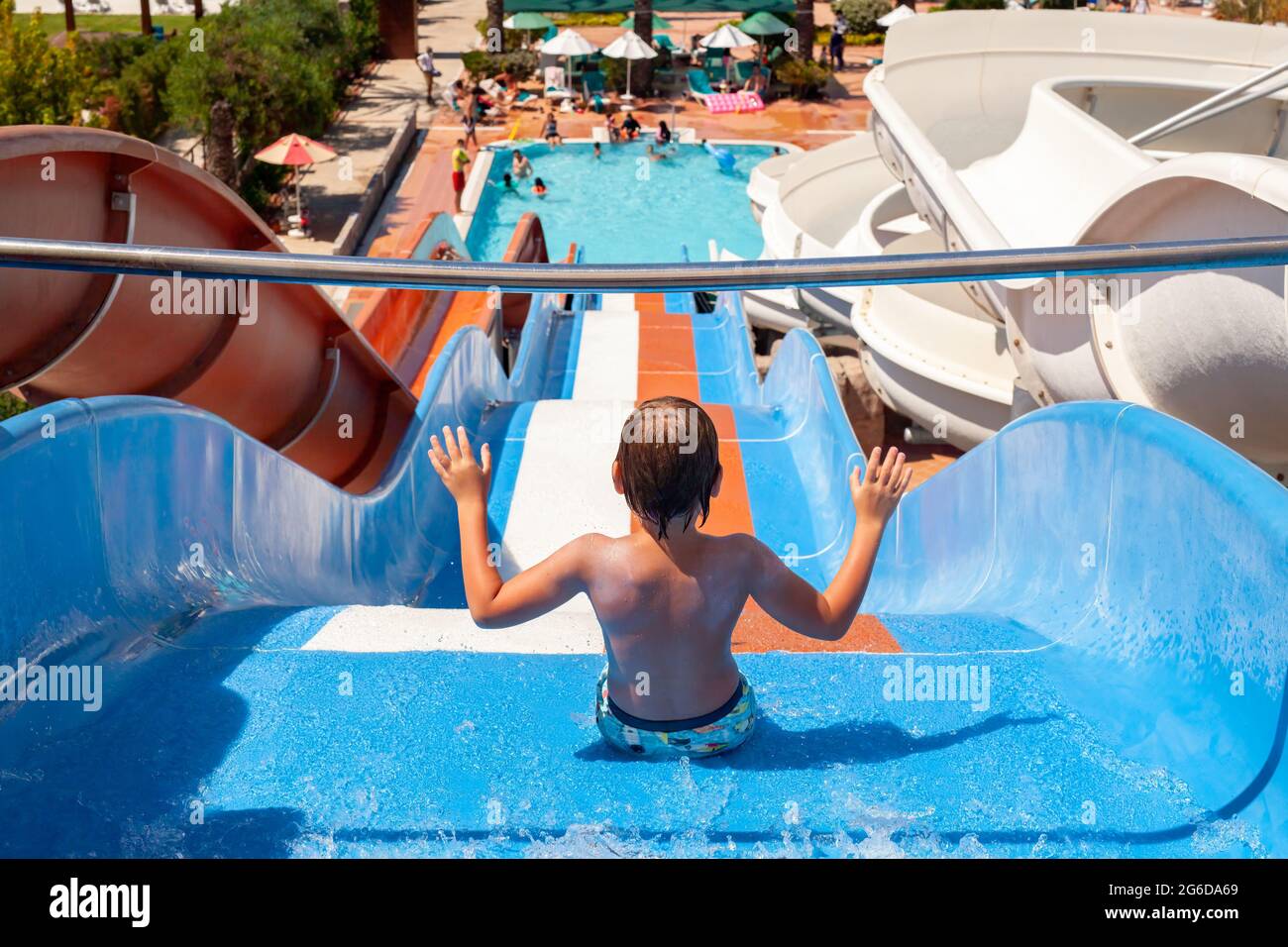 Antalya, Türkei-30. Juni 2021: Foto auf der Rückseite des kleinen Jungen, der in den Sommerferien auf einer großen, farbenfrohen Wasserrutsche im Aquapark untergeht. Sommerurlaub für Kinder Stockfoto