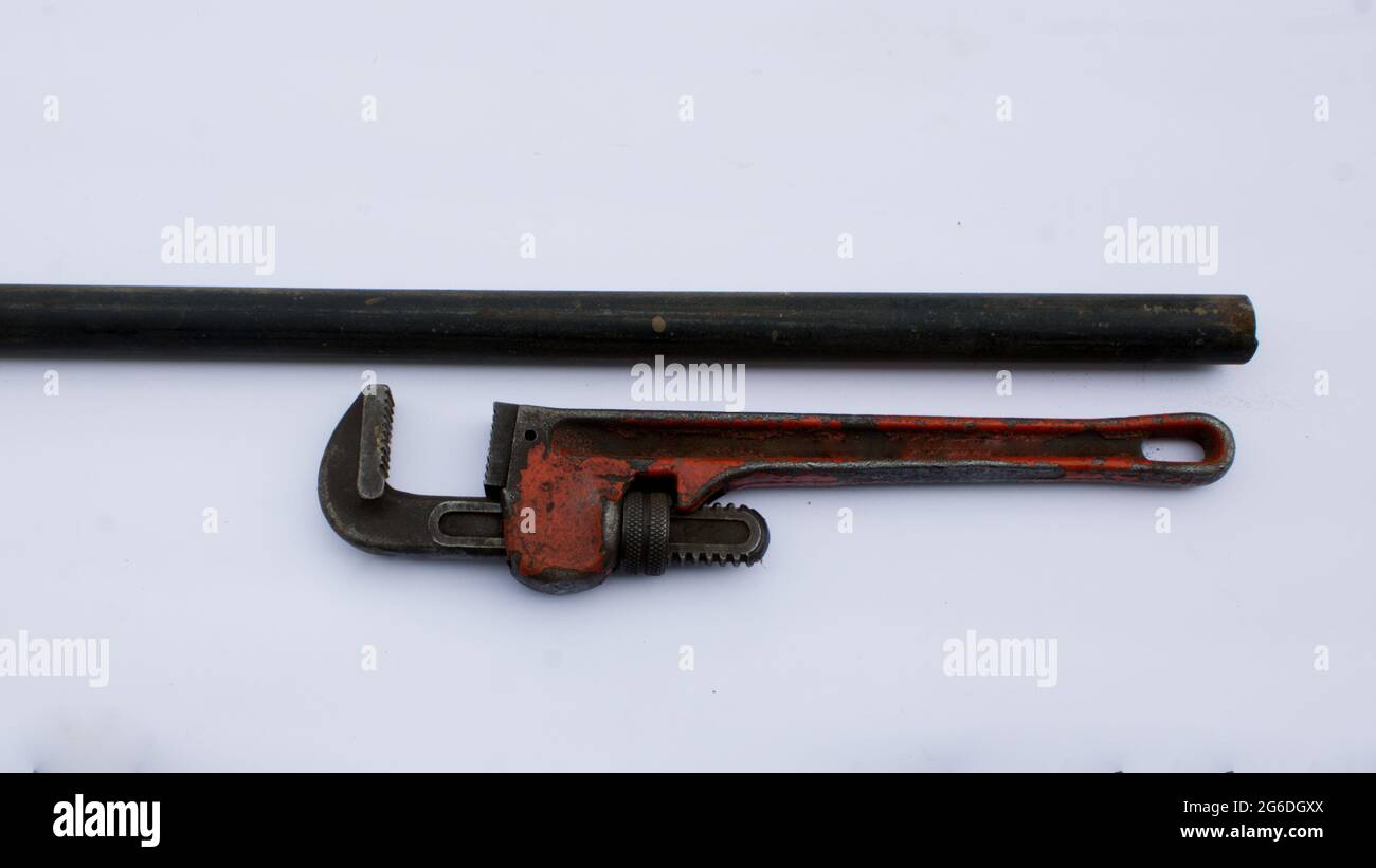 Ein alter Rohrschlüssel und eine schwarze Eisenpfeife Stockfoto