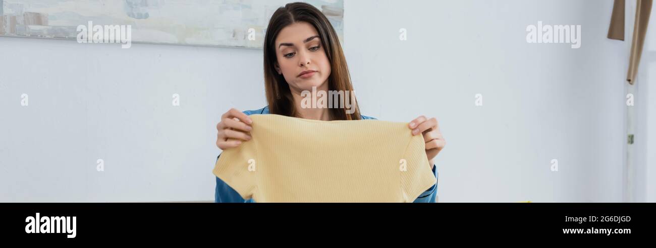 Unzufrieden Frau, die zu Hause T-Shirt ansieht, Banner Stockfoto