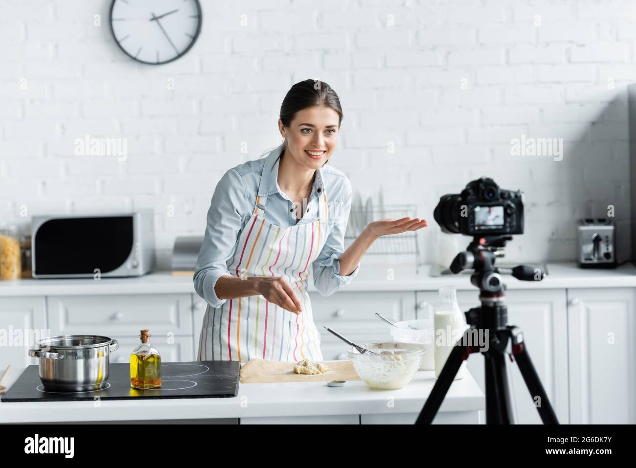 Fröhliche kulinarische Blogger zeigt mit der Hand in der Nähe von Teig und verschwommene Digitalkamera Stockfoto