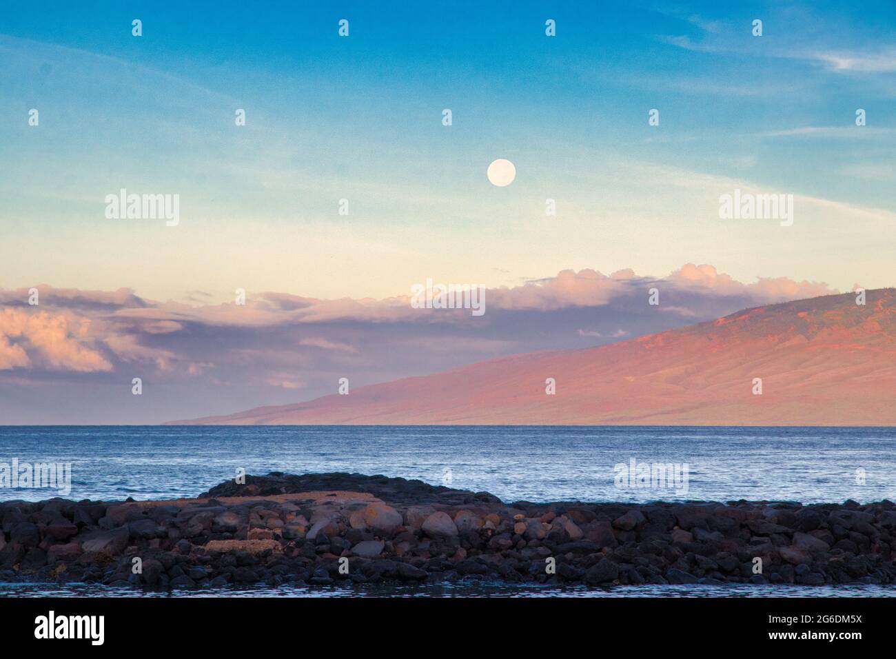 Monduntergang über dem Hafen von Lahaina bei Sonnenaufgang mit Lanai in der Ferne. Stockfoto