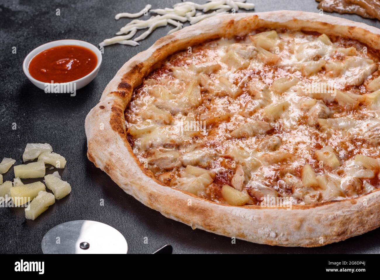 Frische leckere italienische Pizza mit Huhn, Tomaten und Ananas auf dunklem Beton. Italienische Küche Stockfoto