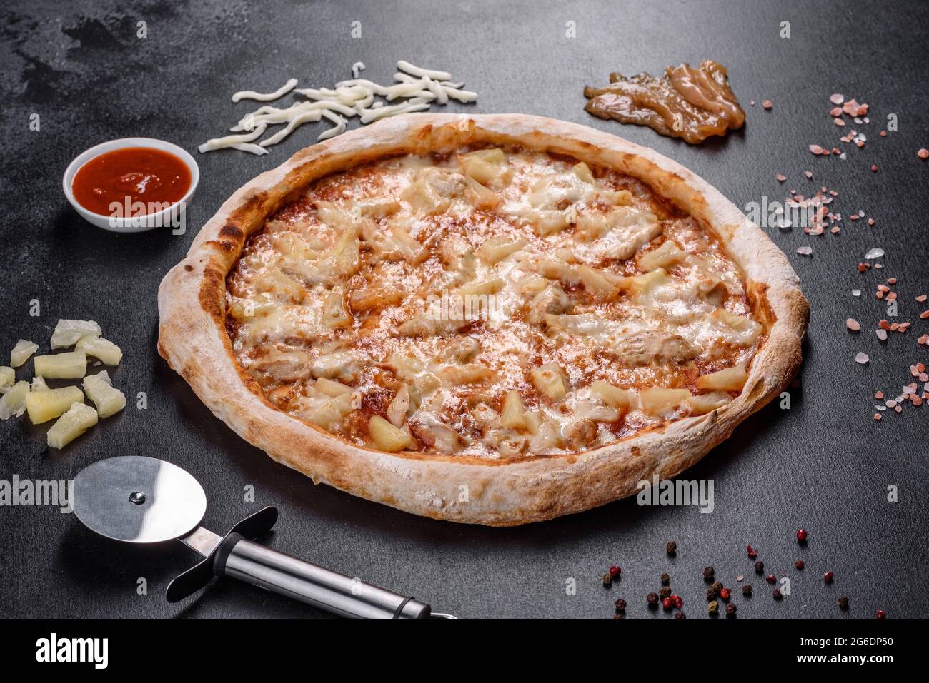Frische leckere italienische Pizza mit Huhn, Tomaten und Ananas auf dunklem Beton. Italienische Küche Stockfoto