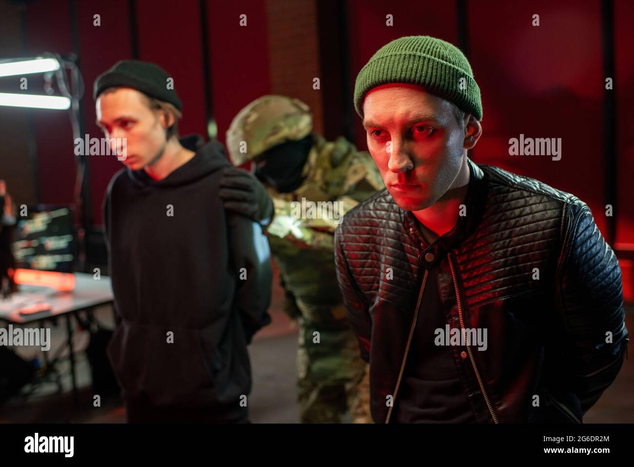 Zwei verhaftete Hacker in schwarzen Jacken, die vor der Kamera standen Stockfoto