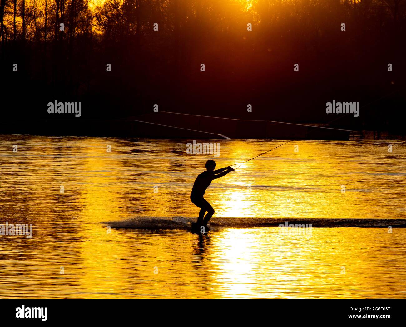 Silhouette eines Athleten, der bei Sonnenuntergang auf einem Wasserski reitet Stockfoto