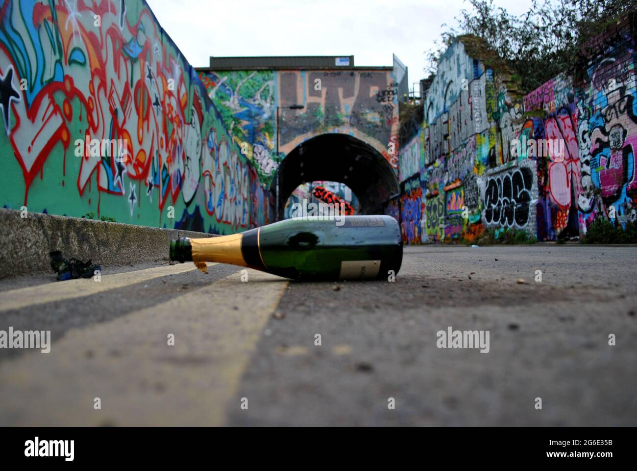 Eine ausrangierte Champagnerflasche liegt auf dem Fleet Street Hill, umgeben von Graffiti-Wänden. Stockfoto