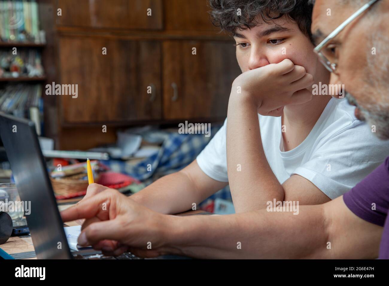 Großvater lehrt seinem Enkel eine Lektion auf einem Laptop-Monitor zu Hause Stockfoto