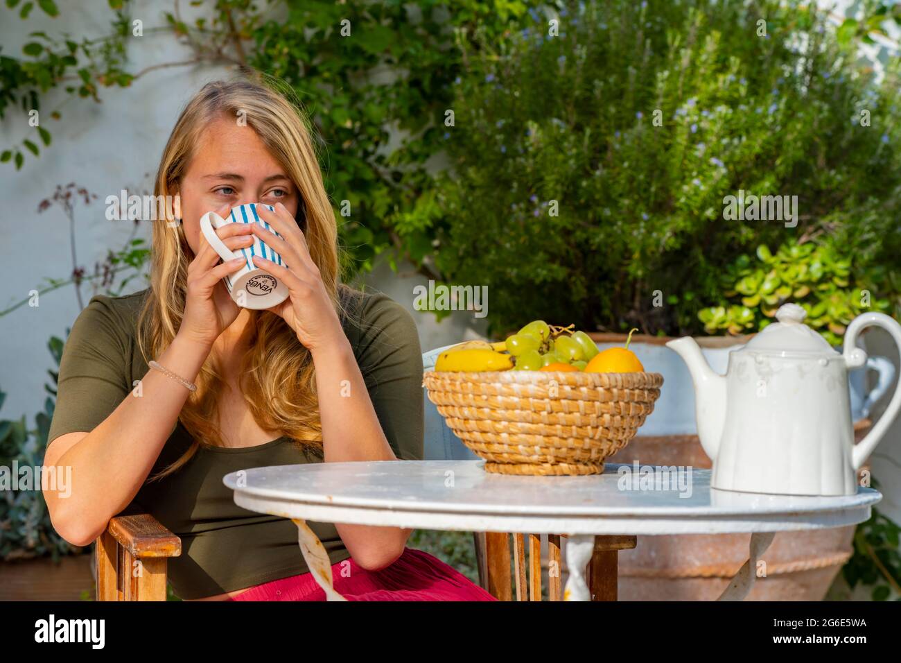 Junge Frau hält Tasse, Frühstück im Urlaub außerhalb, Griechenland Stockfoto