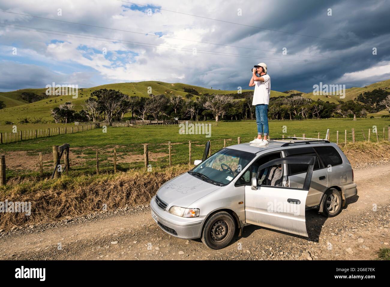 Mann auf dem Autodach, der Fotos macht, Fletcher Bay, Coromandel, North Island, Neuseeland Stockfoto