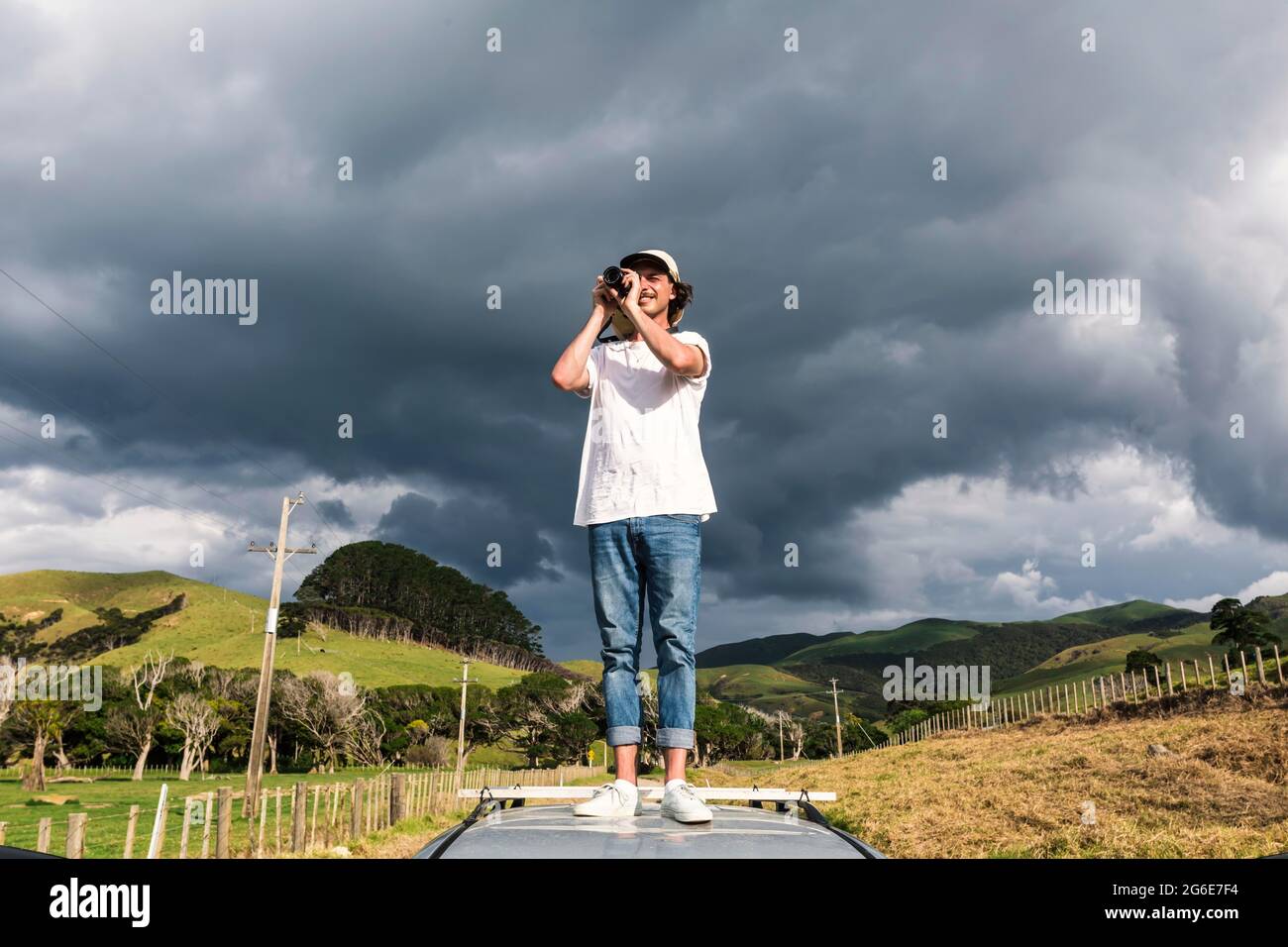 Mann auf dem Autodach, der Fotos macht, Fletcher Bay, Coromandel, North Island, Neuseeland Stockfoto